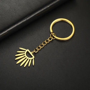 Macro view of golden stainless steel keychain with sunburst geometric pendant and link chain