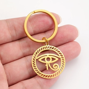 Macro detail of golden stainless steel Eye of Horus pendant held in hand for scale
