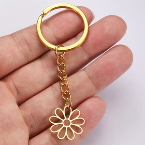 Golden stainless steel hollow flower keychain with hanging chain held in hand