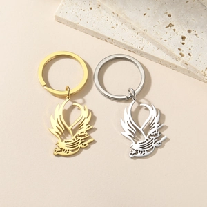 Golden and silver bird silhouette keychains with hollow art design on stone background
