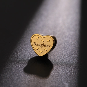 Macro shot of a golden heart charm engraved with Daughter text and small heart motifs