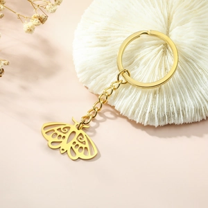 Porte-clés papillon en acier inoxydable doré avec des détails ajourés sur fond beige