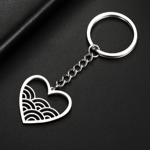 Detailed view of polished stainless steel heart keychain with hollow wave pattern on black leather