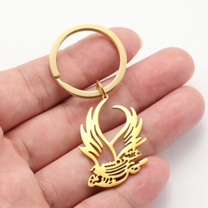 Detailed close-up of a golden bird keychain pendant held in hand for size reference