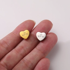 Macro detail of heart-shaped Mom charm in polished gold and silver stainless steel