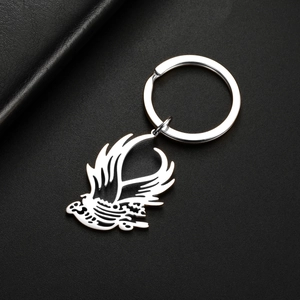 Close-up of polished stainless steel eagle keychain on a premium black leather background