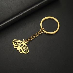 Détail macro du porte-clés papillon doré évidé sur une surface en cuir noir élégant