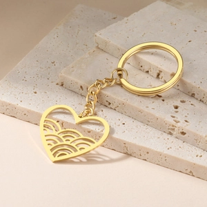Detailed view of heart-shaped keychain with hollow wave pattern on beige stone background