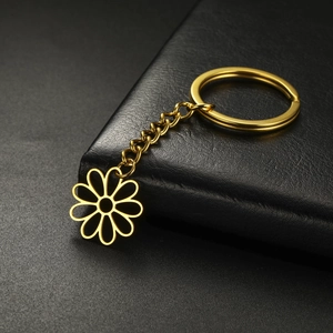 Close-up of golden hollow flower keychain with polished metallic finish on leather