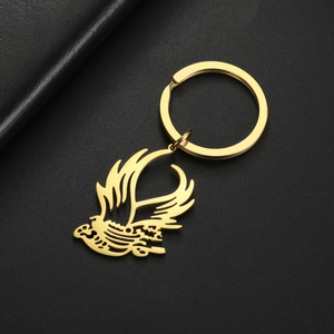 Macro detail of a golden flying bird pendant on a polished stainless steel keychain