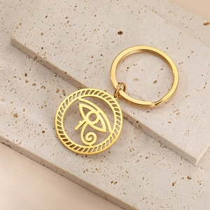 Detailed close-up of golden Horus Eye stainless steel keychain on a stone display