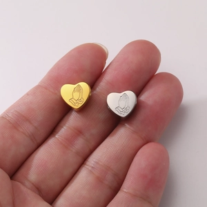 Detailed macro view of heart-shaped stainless steel beads with praying hands engraving