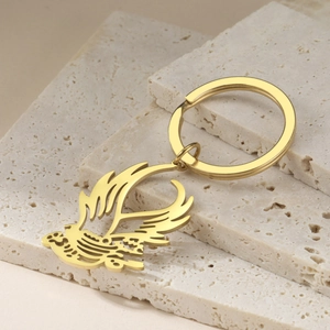 Detailed view of a gold phoenix pendant keychain with intricate hollow cutouts on stone blocks