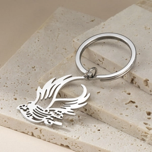 Macro detail of bird pendant keychain made of polished stainless steel on stone