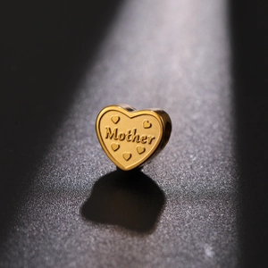 Macro shot of gold heart-shaped charm with Mother engraving and small relief hearts