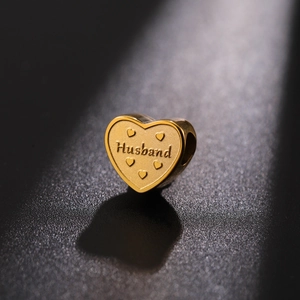 Macro shot of gold heart charm bead with Husband engraving and embossed heart details
