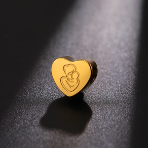 Macro shot of gold heart bead with mother and child engraving for DIY jewelry making