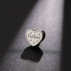 Macro shot of stainless steel heart charm bead with Father engraving and tiny hearts