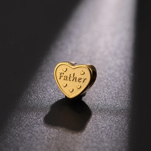 Macro detail of a golden heart charm with Father engraving and five small heart motifs