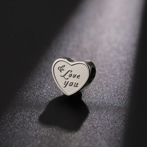 Close-up of heart-shaped stainless steel bead with Love you engraving for DIY jewelry