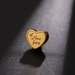 Macro detail of a gold heart charm with I Love You engraving for DIY bracelets