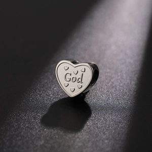 Macro shot of a silver heart-shaped DIY charm featuring God engraving and embossed hearts