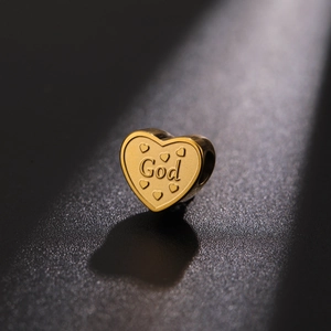 Macro shot of gold heart-shaped charm with God engraving and embossed hearts detail