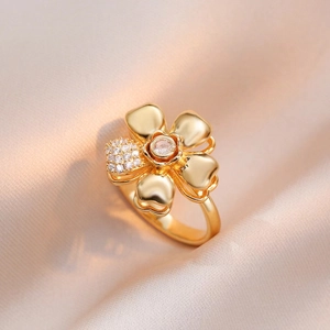 Elegante anillo de flor dorada giratoria con pétalos de circón sobre fondo de seda suave