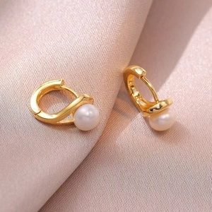 Boucles d'oreilles dorées en S avec perles d'eau douce sur fond en soie rose