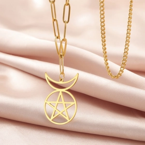 Detalle del colgante de pentagrama y luna en acero dorado con cadena de eslabones