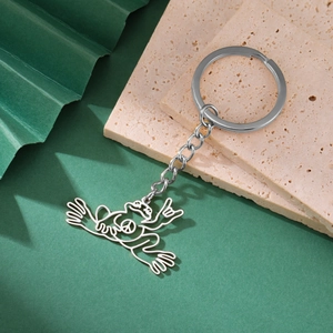 Minimalist stainless steel frog keychain with hollow peace sign pendant on stone background