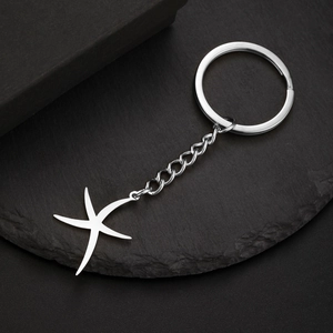 Porte-clés en acier inoxydable poli avec pendentif étoile de mer sur surface noire