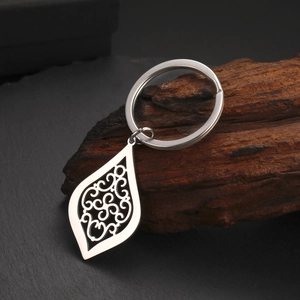 Porte-clés punk en acier titane avec pendentif goutte ajouré sur fond de bois