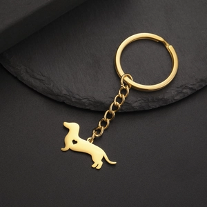 Detail of golden dachshund keychain with heart cutout on dark textured stone background