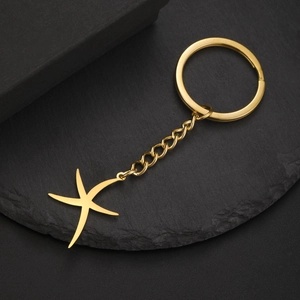 Porte-clés étoile de mer dorée avec chaîne et anneau sur un fond sombre texturé