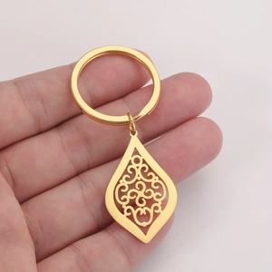Détail d'un pendentif en forme de goutte dorée avec des motifs de vigne en filigrane fin