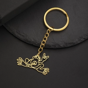 Close-up of golden stainless steel frog keychain with peace symbol on a black stone base