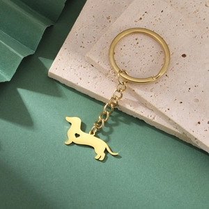 Close-up of golden dachshund keychain with a heart-shaped cutout on dark green background