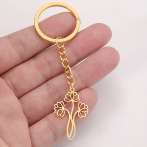 Détail d'un porte-clés doré avec pendentif en fleur de lotus tenu à la main par l'usager
