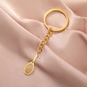 Gros plan du pendentif raquette de tennis dorée sur un tissu élégant en satin rose doux