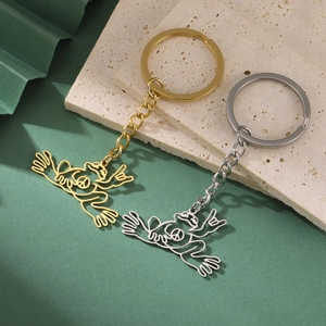 Detailed close-up of hollow frog keychains in gold and silver finish on textured stones