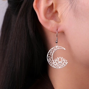 Close-up of stainless steel lotus flower crescent earrings worn on a female model