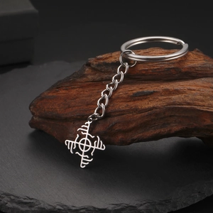 Detail of silver stainless steel rune pendant keychain resting on rustic dark wood