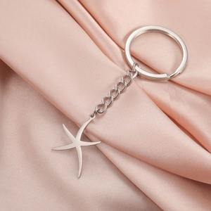 Détail macro d'un porte-clés étoile de mer en acier inoxydable sur de la soie champagne