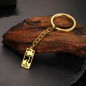 Gros plan d'un porte-clés doré en acier inoxydable avec pendentif palmier et vague