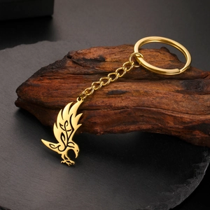 Detail of a golden eagle keychain featuring tribal patterns on dark wood and stone
