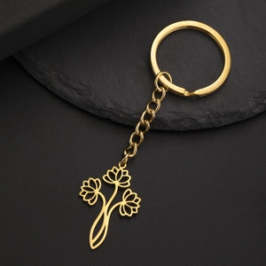 Détail d'un porte-clés en acier doré avec pendentif lotus évidé sur fond noir