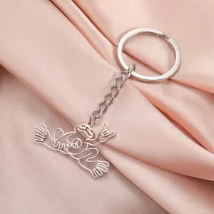 Detailed view of hollow frog keychain with peace sign on pink satin fabric background