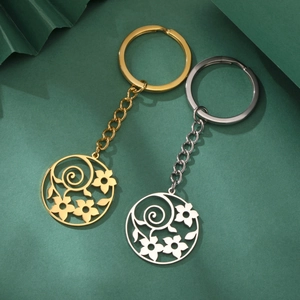Symmetric view of gold and silver hollow flower stainless steel keychains on green background