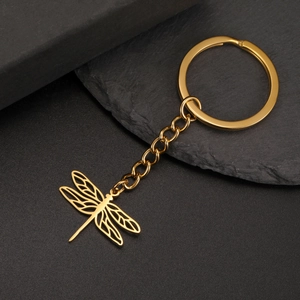 Detail van gouden holle libel hanger en sleutelhanger op donkere stenen ondergrond